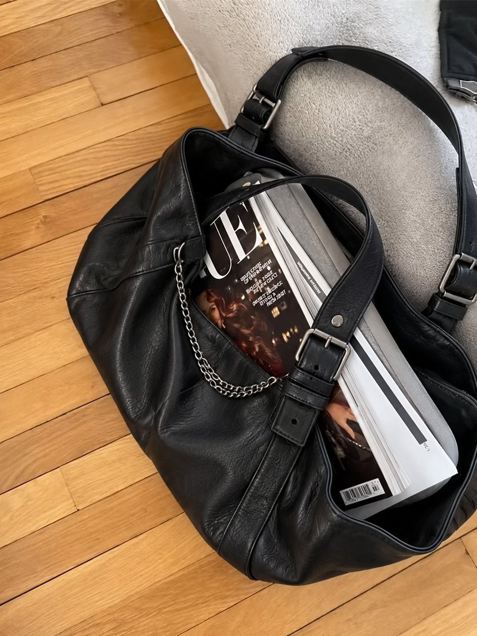 Black slouchy shoulder bag with buckled straps and a silver chain